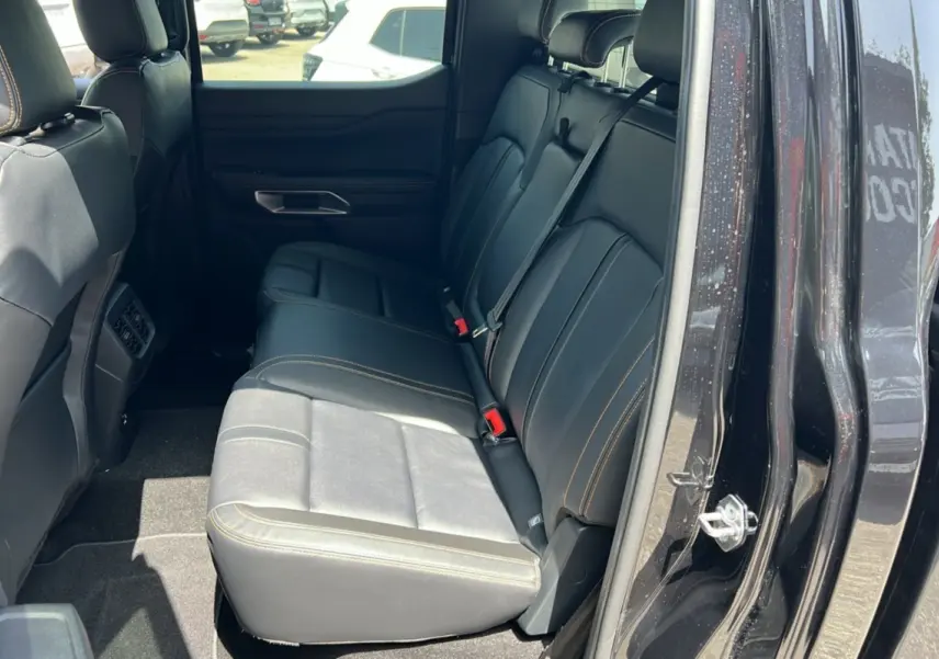 Vue intérieure côté droit sur la banquette arrière en cuir noir avec surpiqûres orange du Ford Ranger Wildtrak Plus 2025.