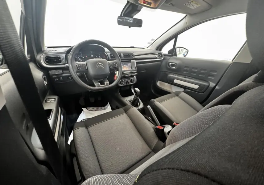Vue intérieure avant de la Citroën C3 2021, sièges gris, tableau de bord avec volant multifonctions et écran tactile central.