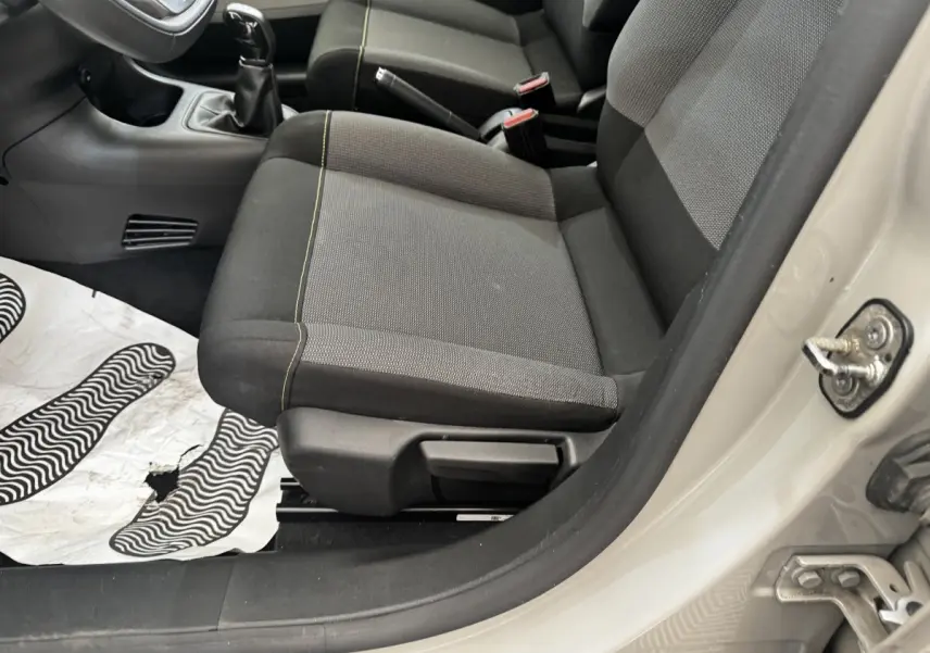 Vue intérieure côté conducteur de la Citroën C3 beige 2021, montrant les sièges avant en tissu gris et noir avec surpiqûres jaunes.