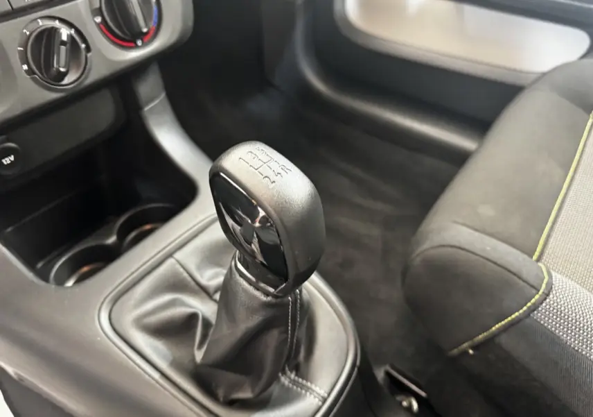 Gros plan sur le levier de vitesses manuel noir dans l’habitacle d’une Citroën C3 beige, avec console et siège partiellement visibles.