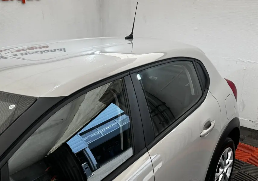Vue côté droit arrière d'une Citroën C3 beige 2021 avec poignées et jantes visibles en intérieur showroom.