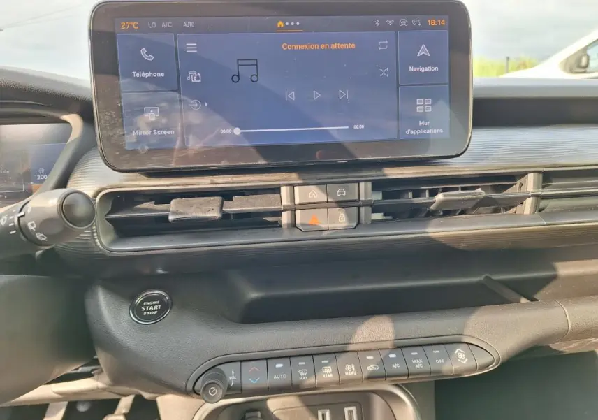 Vue intérieure du tableau de bord du Jeep Avenger 2025 avec écran tactile central et commandes climatisation automatique.