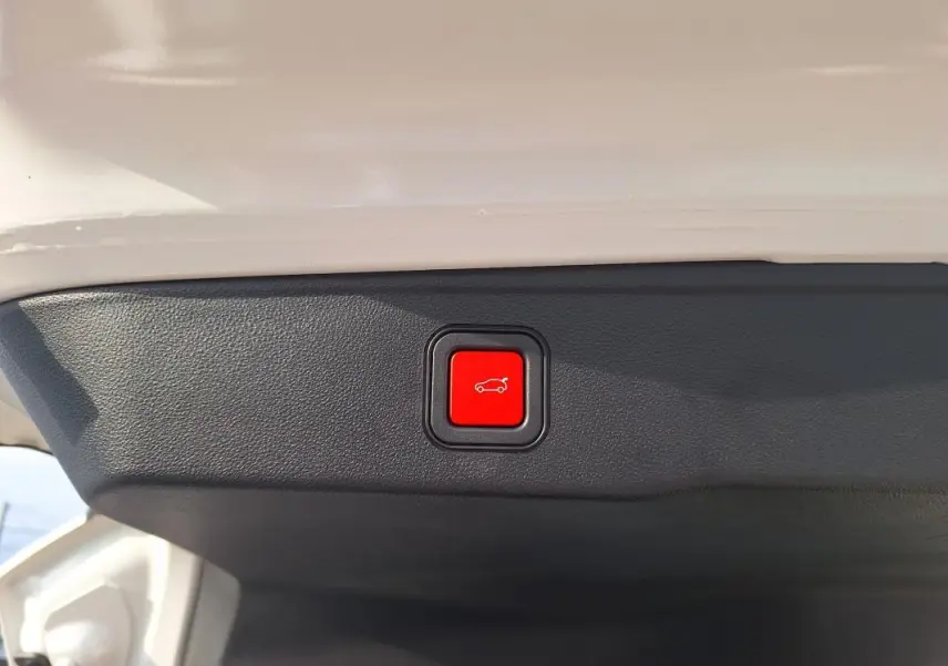Bouton rouge d'ouverture électrique du coffre sur la partie intérieure du hayon blanc du Jeep Avenger 2025.