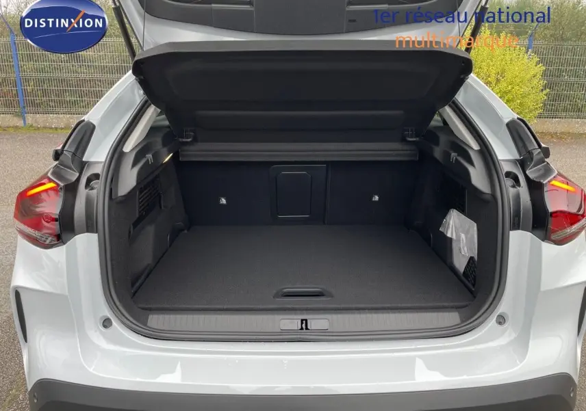 Coffre ouvert vu de l'arrière d'une Citroën C4 blanche métal 2024 avec feux arrière allumés.