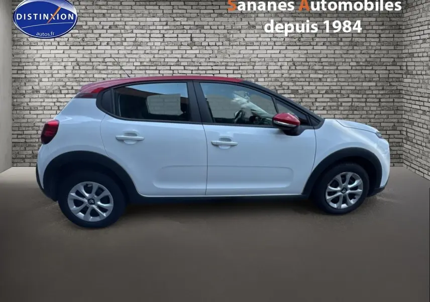 Profil côté gauche d'une Citroën C3 2023 blanc banquise avec toit et rétroviseur rouge, élargisseurs d'ailes noirs.