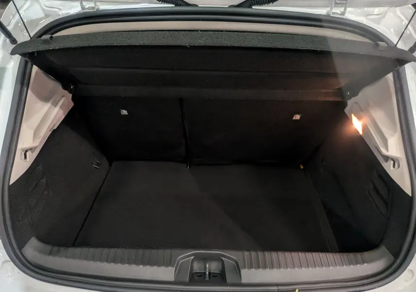 Coffre ouvert vu de l'arrière d'une Renault Clio V Blanc Glacier, montrant l'espace de rangement intérieur noir.