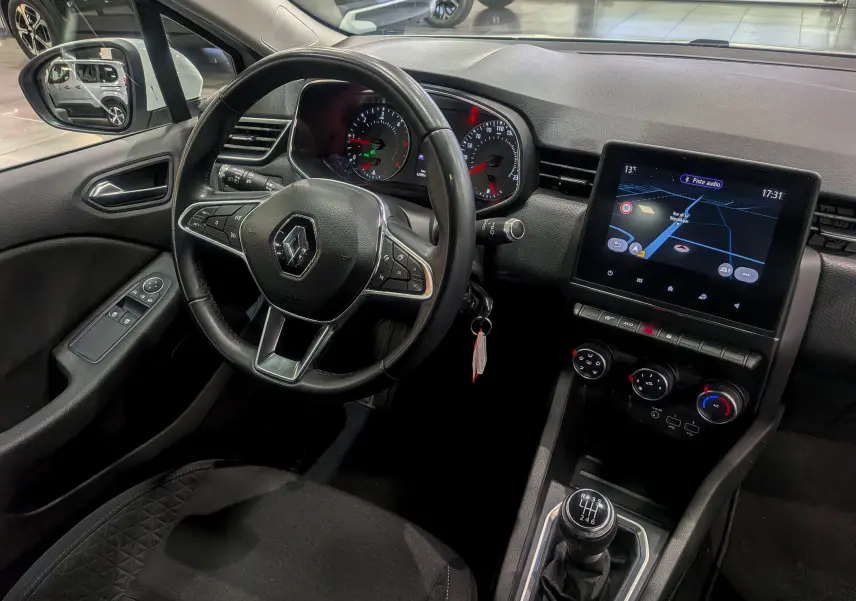 Vue intérieure côté conducteur de la Renault Clio V Business 2020 avec volant multifonction, écran tactile et levier de vitesse manuel.