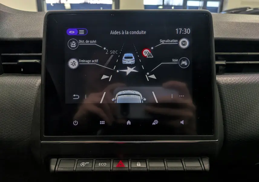 Écran central de la Renault Clio V Business 2020 montrant les aides à la conduite avec interface noire et icônes blanches.