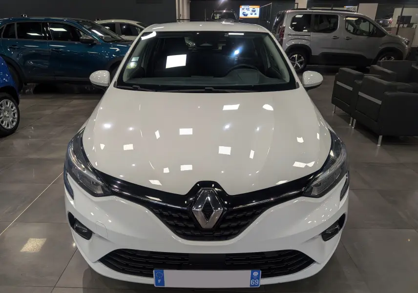 Vue avant d'une Renault Clio V Business blanche Glacier, avec calandre noire brillante et phares LED en showroom.