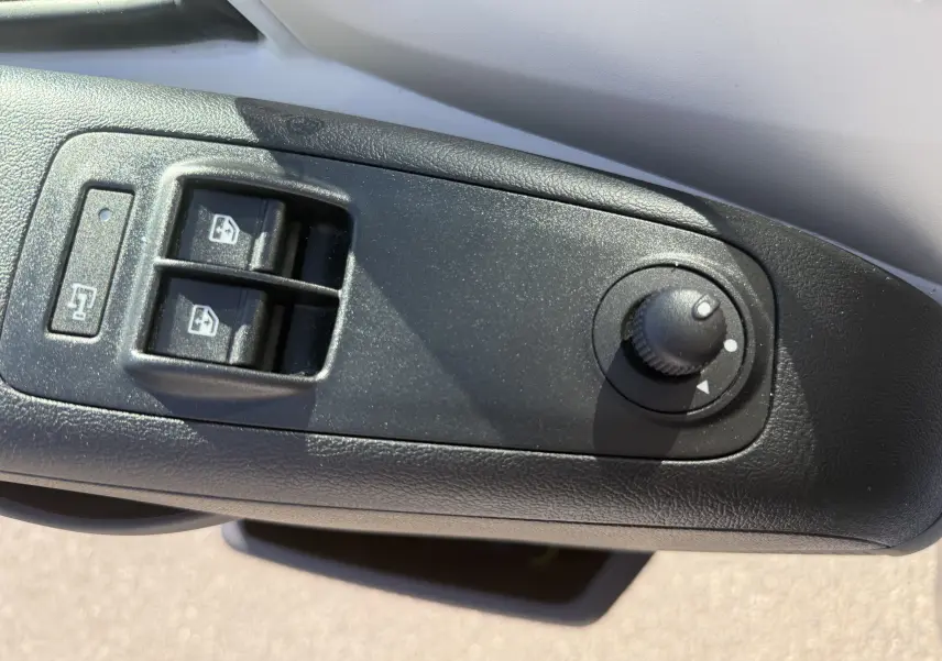 Gros plan sur les commandes de lève-vitres et réglage des rétroviseurs côté conducteur de l’Opel Movano Fourgon blanc.