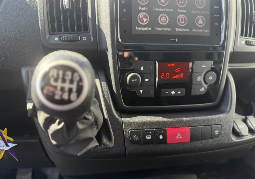 Gros plan sur la console centrale et levier de vitesses manuel de l’Opel Movano Fourgon blanc, avec écran tactile et commandes climatisation.