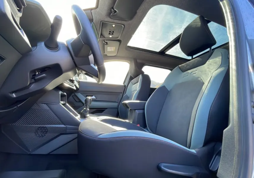 Vue intérieure côté conducteur du Dacia Bigster 2025 avec sièges cuir bi-ton, toit ouvrant panoramique et volant cuir.