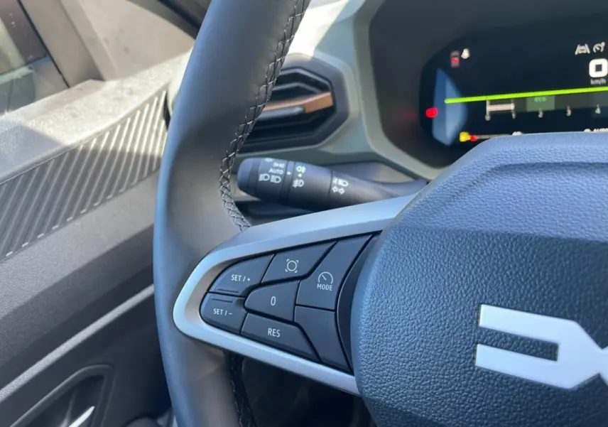 Gros plan sur le volant cuir noir du Dacia Bigster 2025, avec commandes intégrées et tableau de bord digital visible.