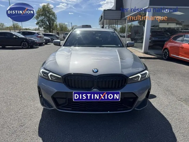 Vue frontale d'une BMW Série 3 320dA xDrive M Sport 2025 en gris métallisé Skyscrapergrau avec calandre noire et phares LED allumés.