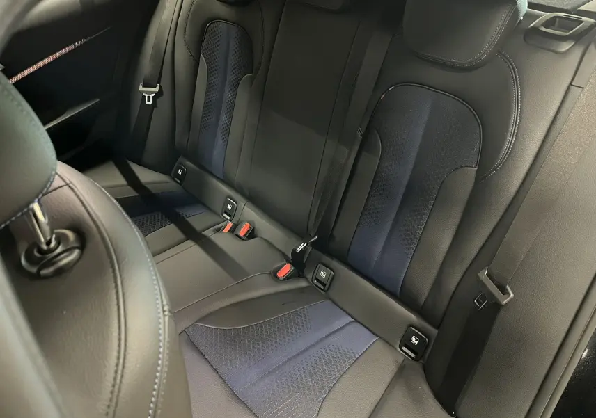 Vue intérieure sur la banquette arrière cuir noir et bleu avec ceintures et fixations ISOFIX d'une BMW Série 1 F40.