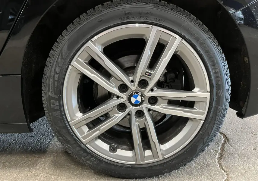 Gros plan sur la jante alliage 17 pouces bi-ton de la BMW Série 1 F40 noire métallisée, avec logo M Sport visible.