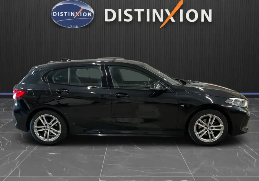 Profil droit d'une BMW Série 1 F40 noire métallisée, finition M Sport avec jantes alliage et vitres teintées.