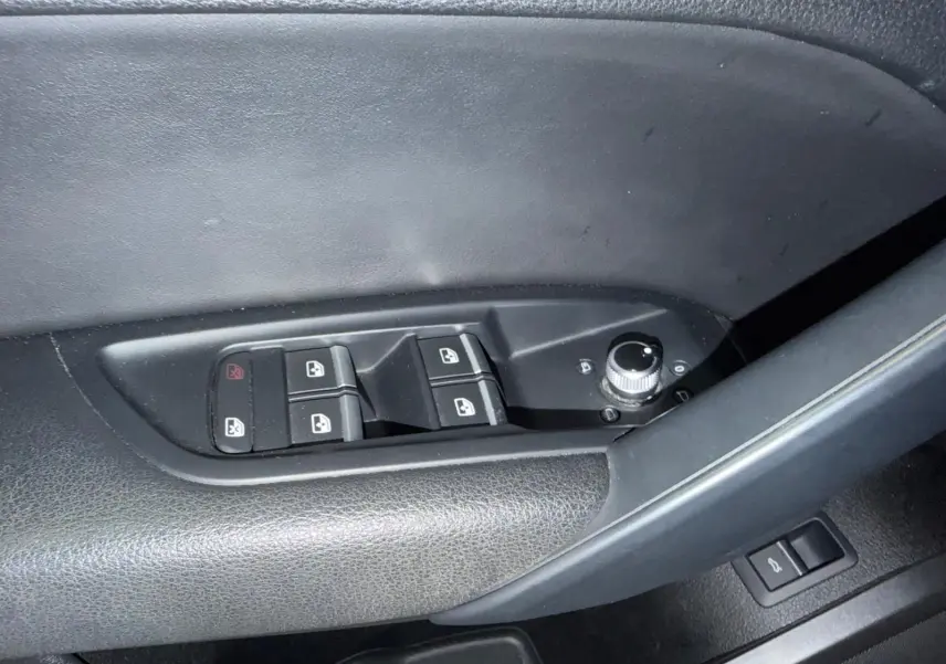 Gros plan sur les commandes de lève-vitres et rétroviseurs côté conducteur d’Audi Q5 Sportback gris, intérieur noir.