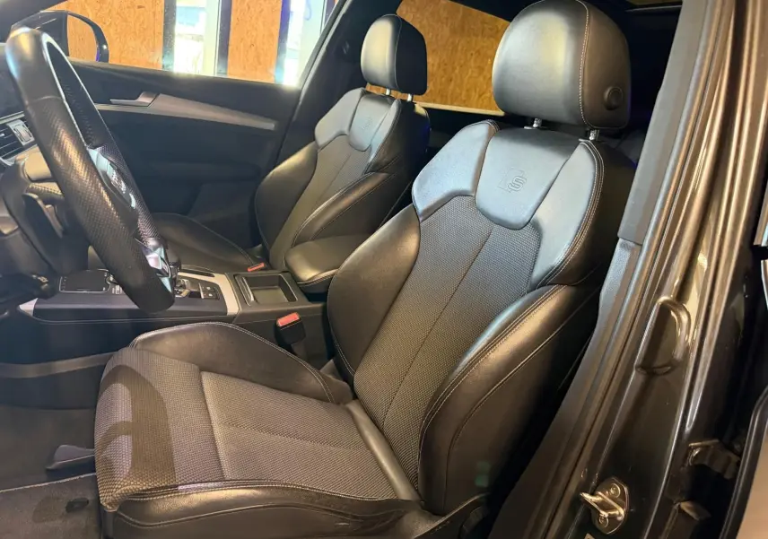 Vue intérieure côté gauche de l'Audi Q5 Sportback 2019 avec sièges avant noirs en cuir et tissu S-Line.