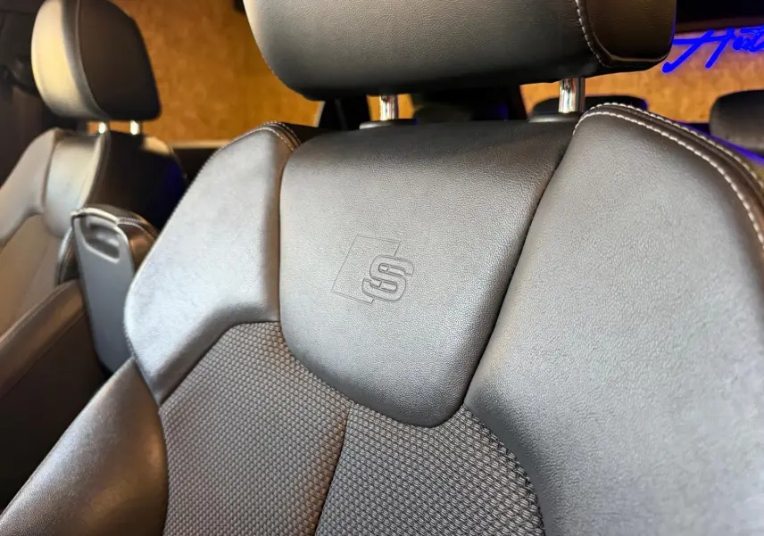Gros plan sur le siège avant en cuir noir avec logo S embossé, intérieur de l'Audi Q5 Sportback gris 2019.