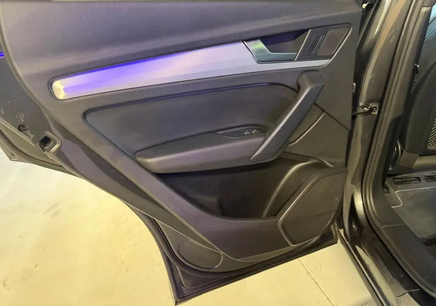 Vue rapprochée de la porte arrière droite gris foncé de l’Audi Q5 Sportback 2019 avec garniture noire et insert aluminium.