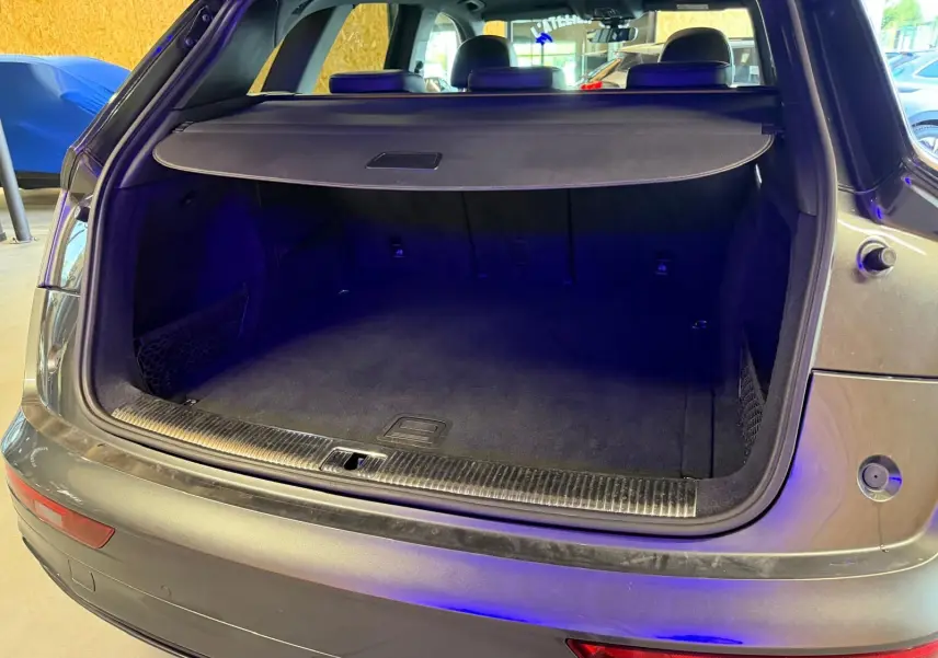 Coffre ouvert vu de l'arrière d'un Audi Q5 Sportback gris 2019, montrant l'espace de chargement vide et la plage arrière.