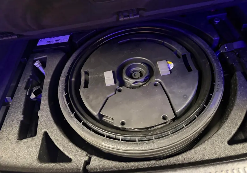 Vue rapprochée de la roue de secours noire dans le coffre d’un Audi Q5 Sportback gris 2019.