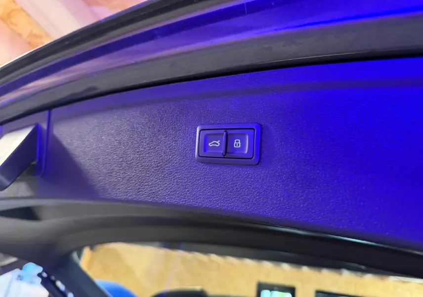 Boutons d'ouverture et de verrouillage électrique du hayon sur la partie intérieure du coffre d'un Audi Q5 gris.
