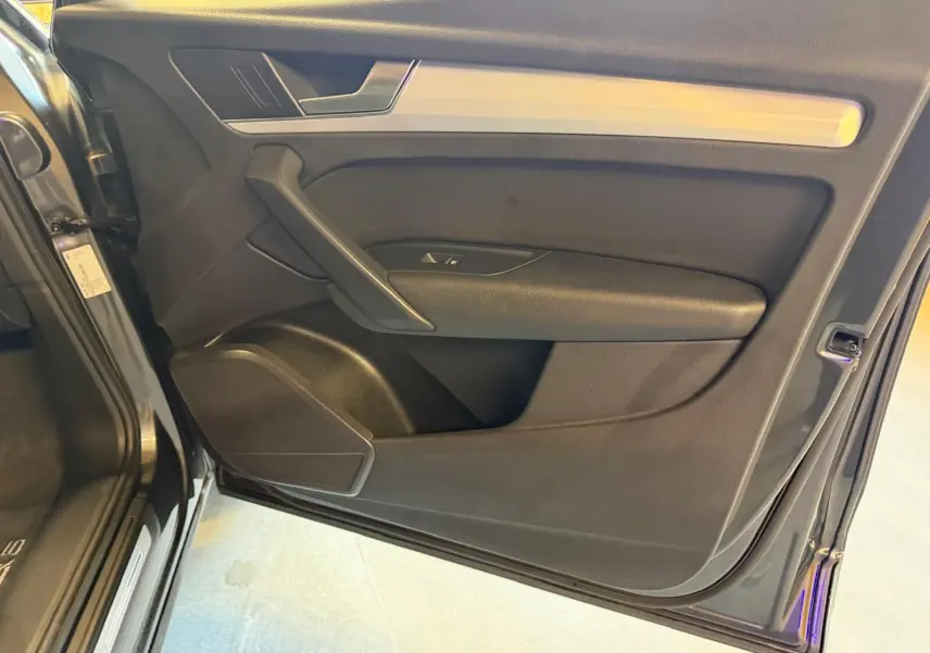 Vue intérieure de la porte avant gauche d’un Audi Q5 gris, avec garniture noire et insert aluminium.