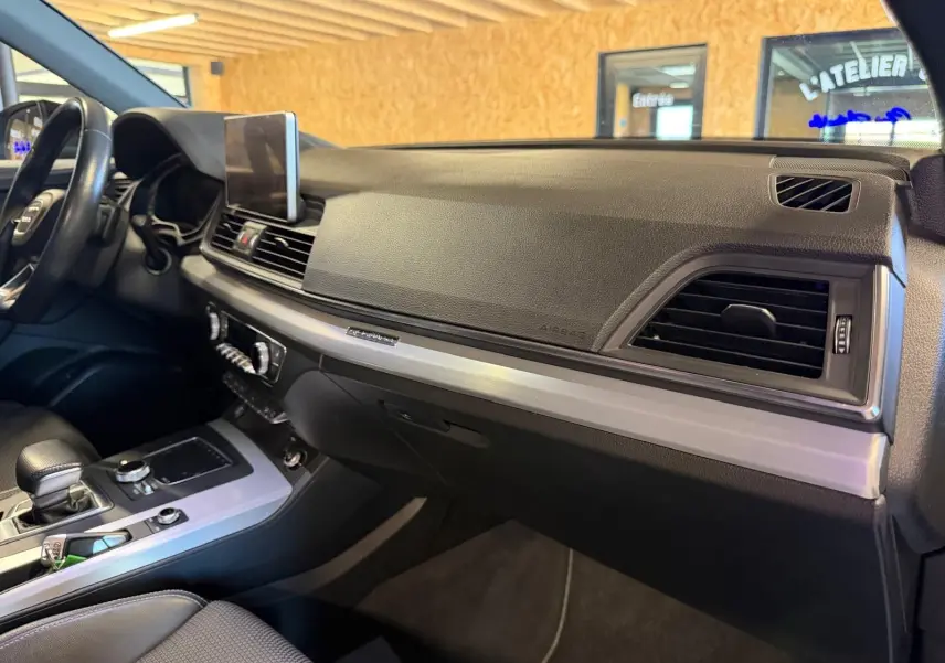 Vue intérieure côté passager du tableau de bord noir et console centrale argentée de l'Audi Q5 Sportback gris 2019.