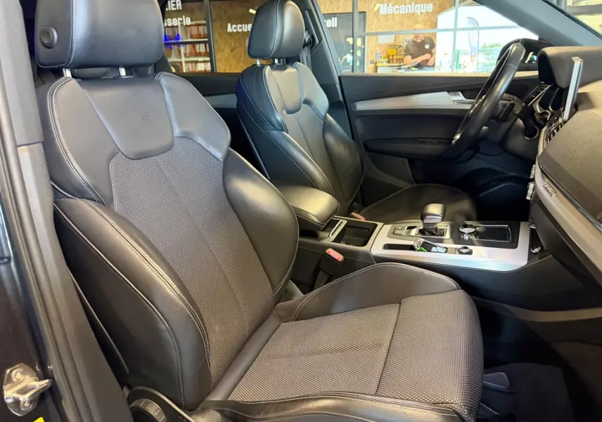 Vue intérieure côté conducteur de l'Audi Q5 Sportback 2019, sièges cuir noir avec console centrale et volant visibles.