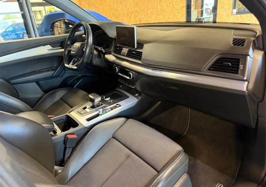 Vue intérieure côté conducteur de l'Audi Q5 Sportback gris, avec tableau de bord moderne et sièges en cuir noir.