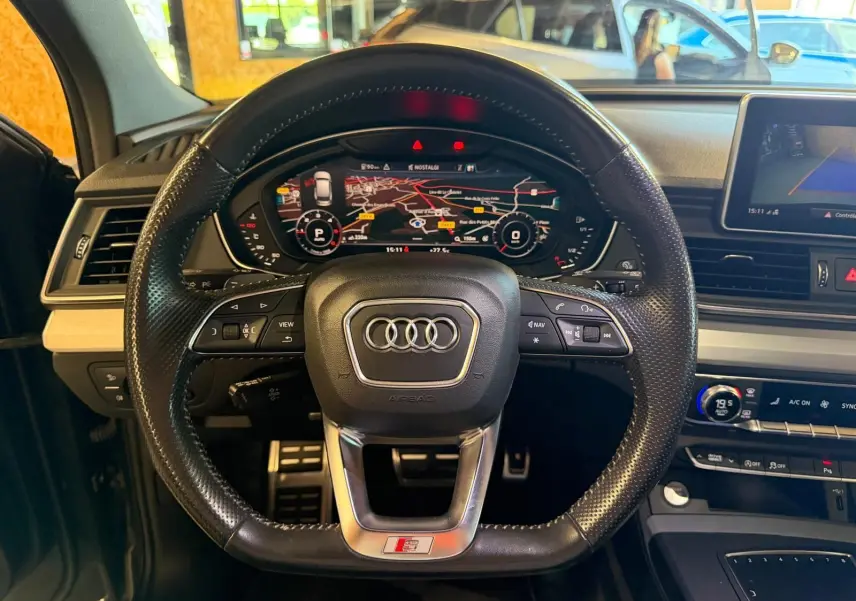 Vue intérieure centrée sur le volant S-Line noir perforé et le tableau de bord numérique de l'Audi Q5 Sportback 2019.