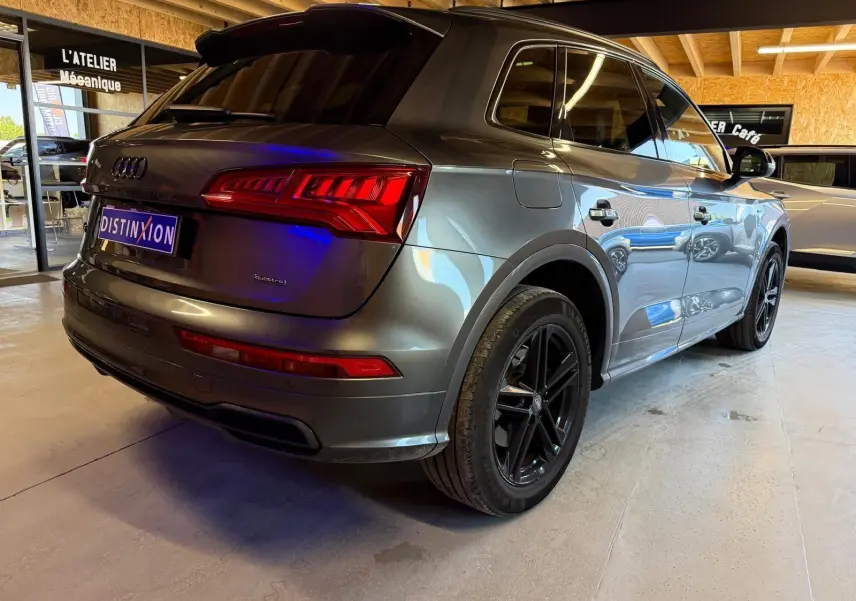 Vue 3/4 arrière droite d'un Audi Q5 Sportback gris métallisé avec jantes noires, stationné en intérieur.