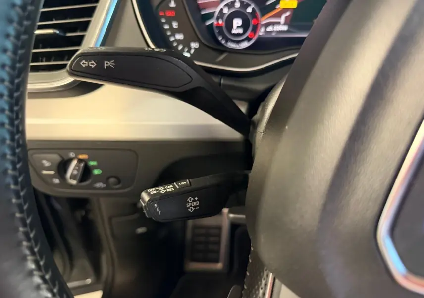 Gros plan sur la commande de régulateur de vitesse et clignotants côté gauche du volant d’un Audi Q5 Sportback gris 2019.