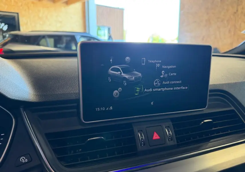 Vue intérieure du tableau de bord de l'Audi Q5 Sportback gris, avec écran central affichant l'interface smartphone.