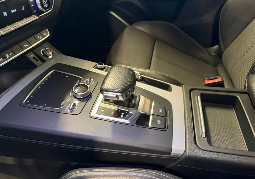 Vue rapprochée de la console centrale et levier de vitesse du Audi Q5 Sportback gris, intérieur noir avec commandes modernes.
