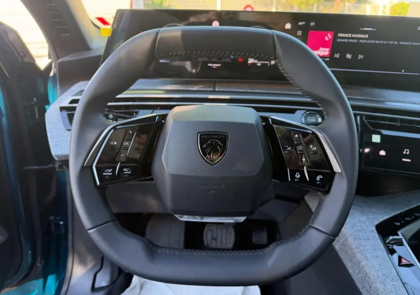 Vue rapprochée du volant cuir noir du Peugeot 3008 Hybrid 145 e-DCS6 Allure bleu 2025, avec commandes intégrées.