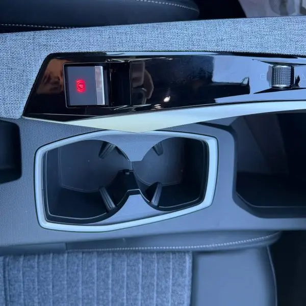 Gros plan sur la console centrale du Peugeot 3008 Hybrid 145 e-DCS6 Allure 2025, avec porte-gobelets et frein à main électrique.
