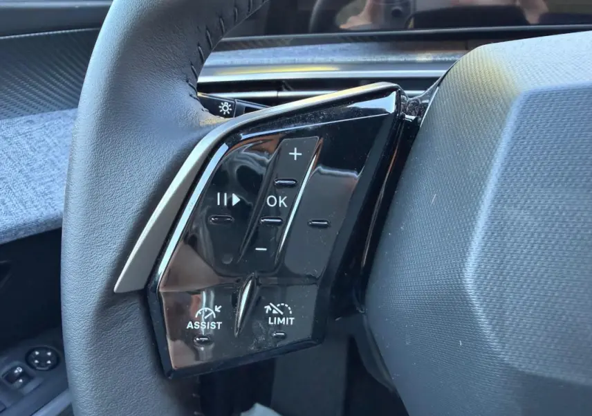 Gros plan sur les commandes au volant côté gauche du Peugeot 3008 Hybrid bleu, avec boutons de régulateur et volume.