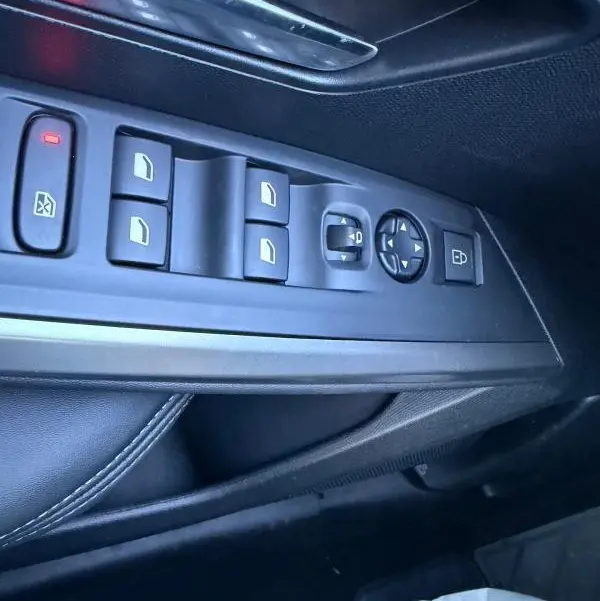 Vue rapprochée des commandes de lève-vitres et rétroviseurs côté conducteur du Peugeot 3008 Hybrid 145 e-DCS6 Allure bleu 2025.