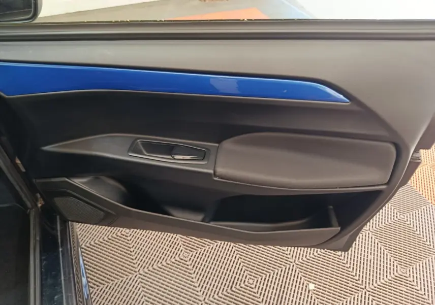 Détail de la porte côté conducteur d'une Aixam Ambition 0.5 City Coupe GTI blanche avec insert bleu, vue intérieure.