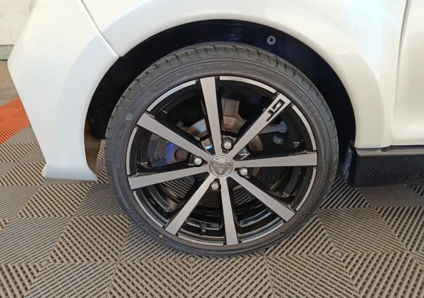 Gros plan sur la roue avant gauche de l'AIXAM AMBITION 0.5 CITY COUPE GTI blanche avec jante noire et argentée.