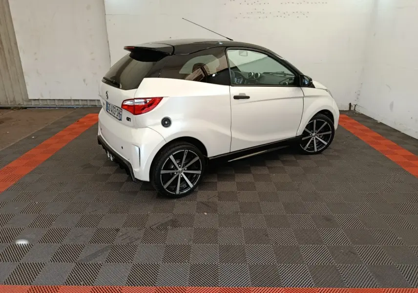 Vue 3/4 arrière droite de l'AIXAM Ambition 0.5 City Coupe GTI blanche avec toit noir et jantes noires.