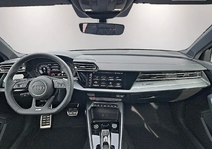Vue intérieure frontale de l'Audi A3 Sportback 2026 avec tableau de bord noir, volant sport et écran tactile central.