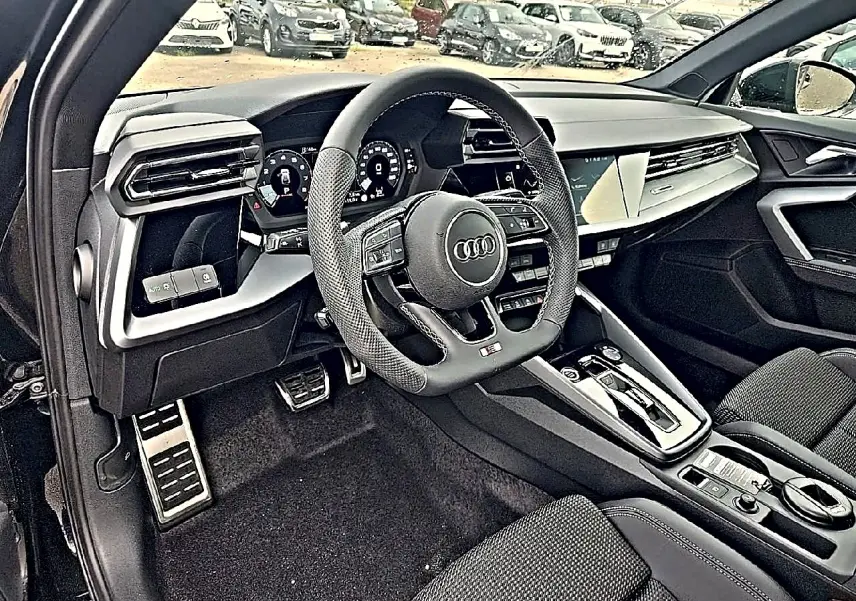 Vue intérieure côté conducteur de l'Audi A3 Sportback 2026, volant sport cuir et tableau de bord digital noir.