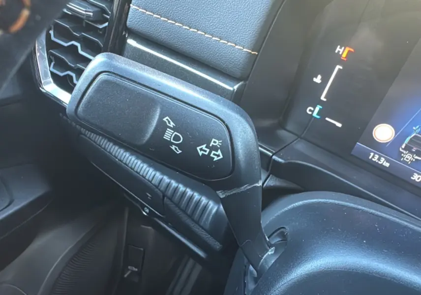 Gros plan sur la commande de clignotants noire dans l’habitacle du Ford Ranger gris carbone, avec tableau de bord partiellement visible.