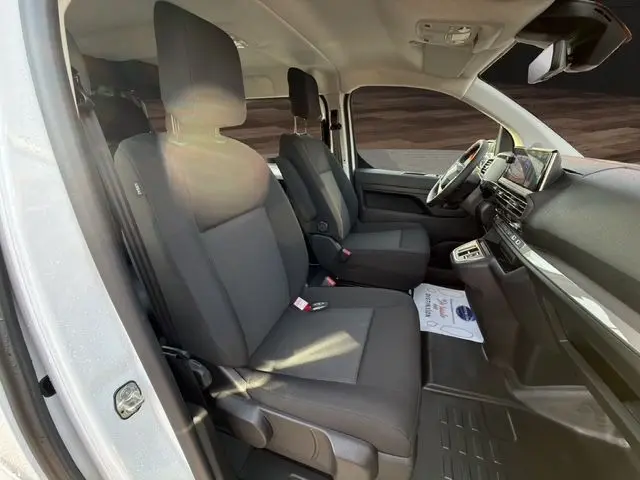 Vue intérieure côté gauche du poste de conduite du Citroën Jumpy Cabine Approfondie blanc avec sièges tissu gris et tableau de bord moderne.