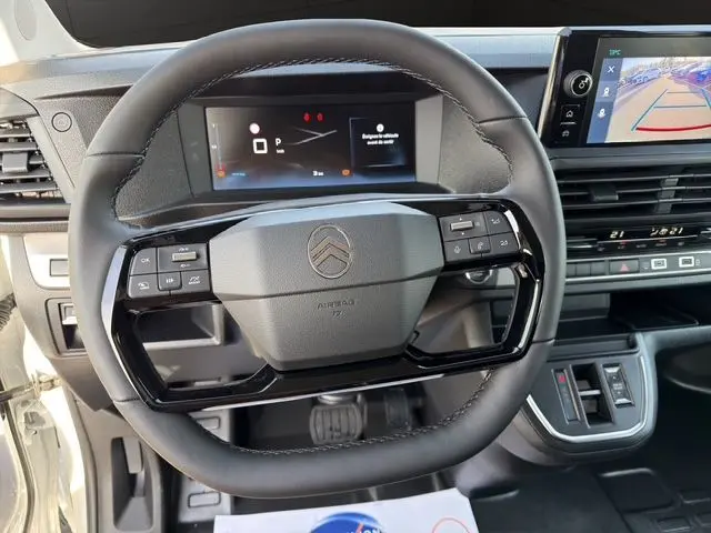 Vue rapprochée du volant cuir noir et du tableau de bord numérique du Citroën Jumpy Cabine Approfondie blanc, avec écran tactile visible.