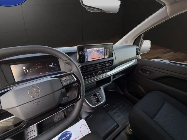 Vue intérieure côté conducteur du Citroën Jumpy blanc, avec tableau de bord numérique et écran tactile de caméra de recul.